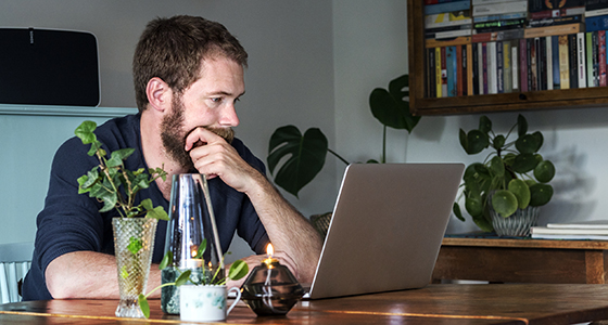 Partainen mies katsoo kannettavaansa tarkistaakseen lainansa