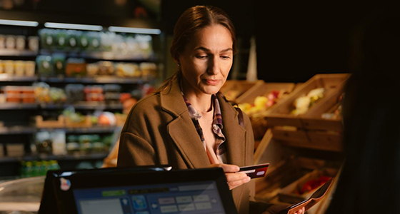 Nainen katsoo puhelintaan kassajonossa